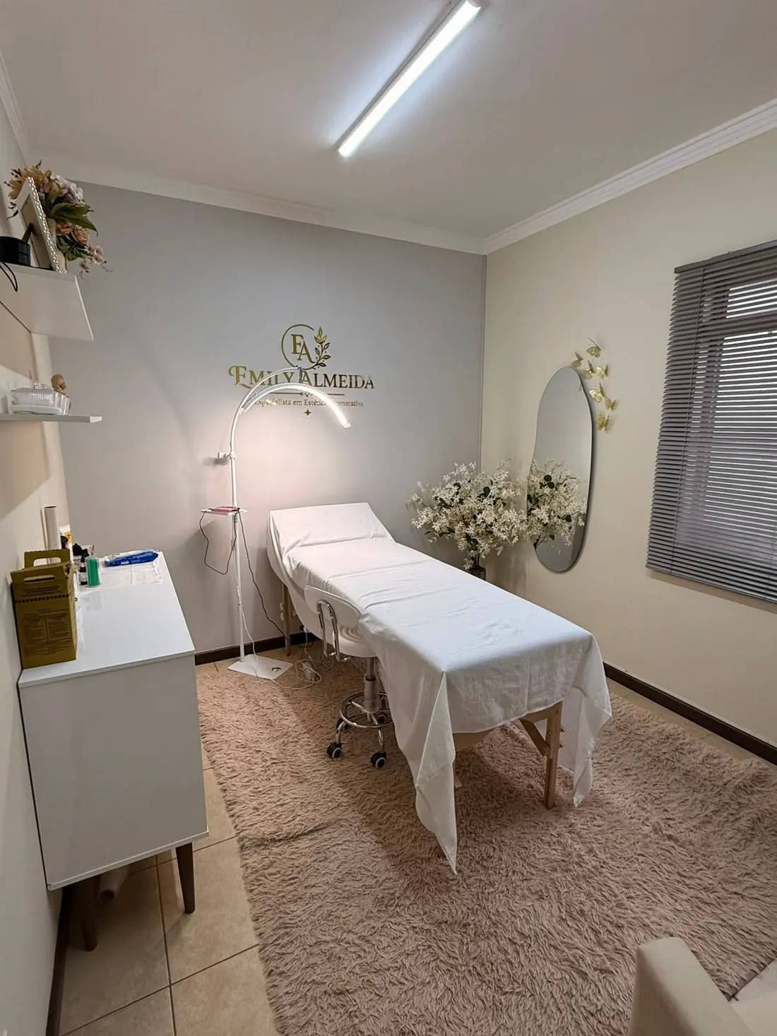 Sala de atendimento da Emily Almeida Estética em Jales, com maca, iluminação de precisão e a logo da marca na parede